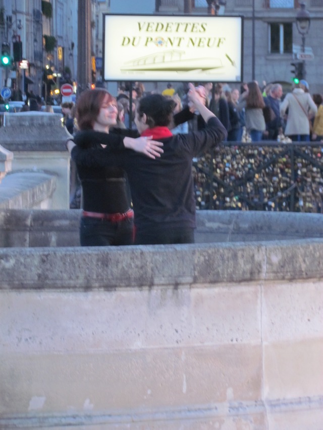 A couple dancing, with music, on one of the bridges at sunset.